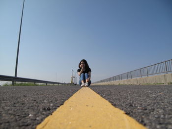 Man cycling on road against clear sky