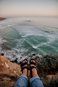 Low section of person on rock in sea