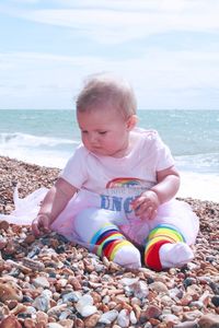 Cute boy sitting on pebbles at beach