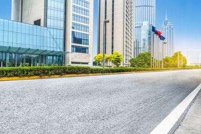 Road by modern buildings against sky in city