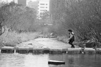 Man standing on riverbank in city