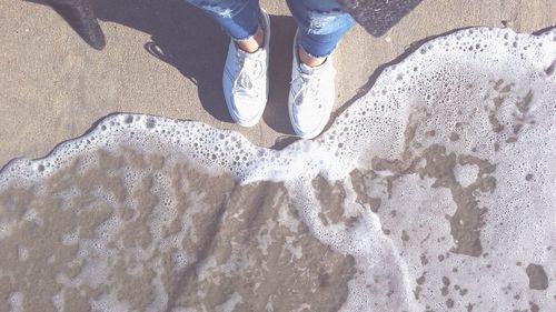 Low section of man standing on sand