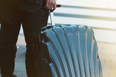 Midsection of businessman carrying suitcase on floor