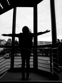 Rear view of silhouette woman standing at airport against sky