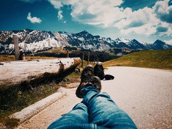 Low section of person on snowcapped mountain against sky