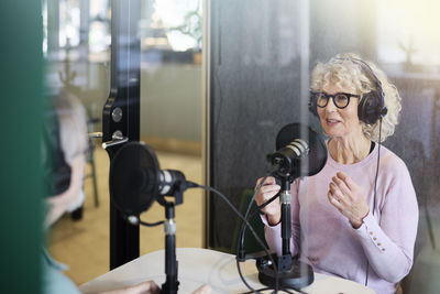 Mature woman sitting and hosting podcast or radio show or podcast