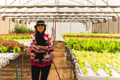 Portrait of young woman standing by plants