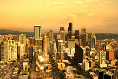 Modern buildings in city against sky during sunset