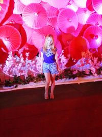 Full length of woman standing on pink umbrella