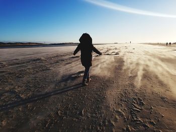 Rear view of woman walking on beach