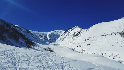 Scenic view of snowcapped mountains against clear blue sky