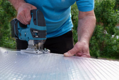 Midsection of man working on wood