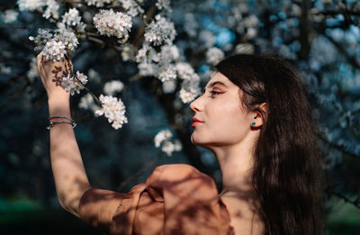 Portrait of woman holding red flowering plant