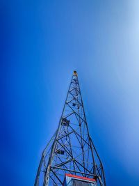 Low angle view of communications tower against clear blue sky