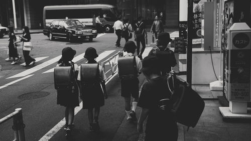 Rear view of school students walking in city