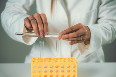 Midsection of female scientist experimenting in laboratory