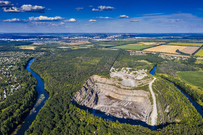 Top view of a stone, granite quarry. beautiful forest, blue sky, clouds. river flows. 