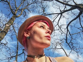 Low angle portrait of woman wearing hat against sky