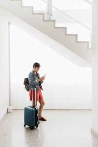 Full length of man using mobile phone while sitting on staircase