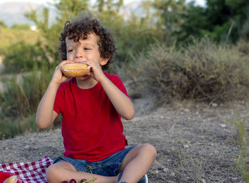 Funny picnic situation of a boy eating a sandwich in the mountains 