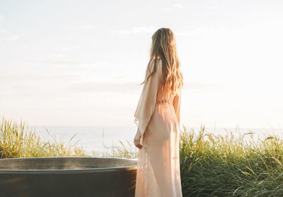 Rear view of woman standing on field against sky