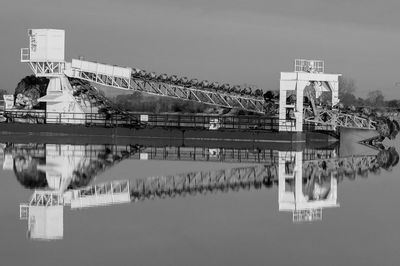 Bridge over river by buildings against sky