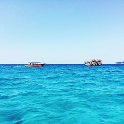 Boats in sea against clear sky