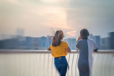 Rear view of women standing in city against sky