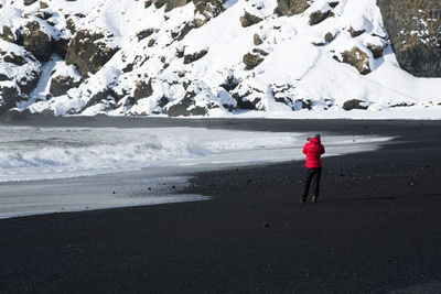 Photographer at the black sand beach in vik, iceland in wintertime
