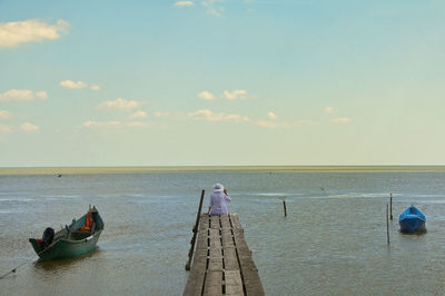 Old rowboats and woman on pier at razim lake, romania