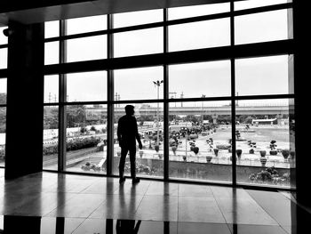 Rear view of man standing by window in airport