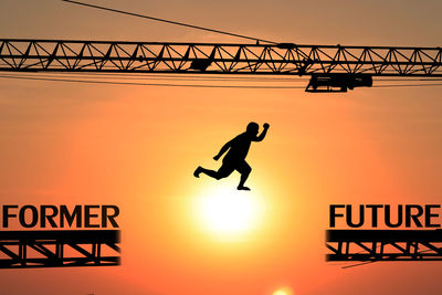 Low angle view of silhouette text on bridge against sky during sunset