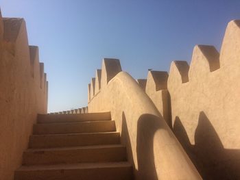 Low angle view of staircase amidst buildings against sky