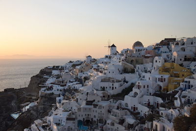 Aerial view of townscape by sea against sky during sunset