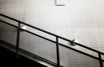 Low angle view of railing against tiled wall at subway