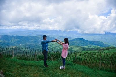 Couple holding hands while standing on mountain