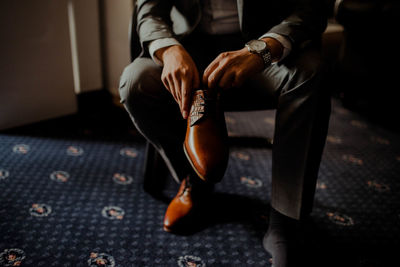 Low section of man getting dressed while standing at home