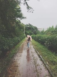 Rear view of person walking on wet footpath