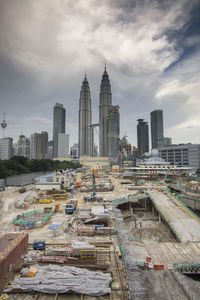 Construction site with petronas towers against cloudy sky