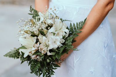 Midsection of bride holding bouquet