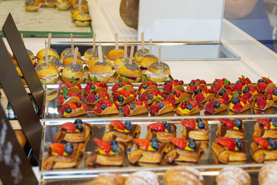 Fruit pastries with strawberries and black cherries and savory sandwiches with cold cuts.