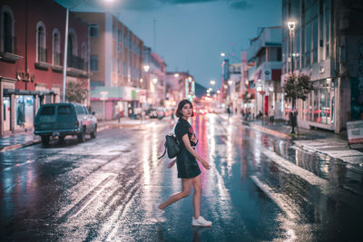 Man walking on wet street at night