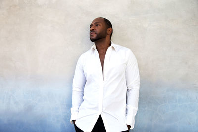 Portrait of young black man standing against wall