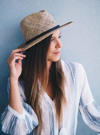 Woman wearing hat against wall