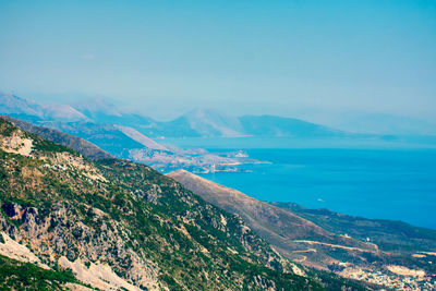 Scenic view of sea and mountains against blue sky