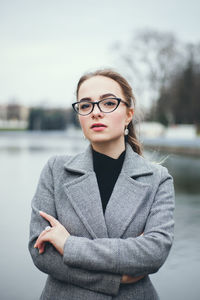 Portrait of young woman standing by lake