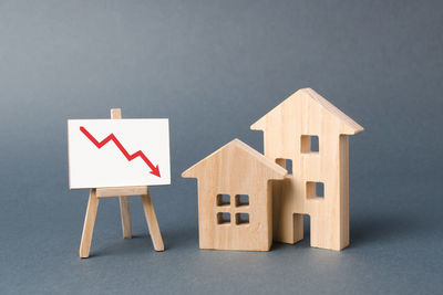 Two wooden houses and a poster with a symbol of falling value. concept of real estate value 