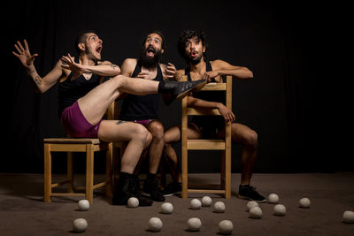 Young jugglers sitting on chairs with balls on stage
