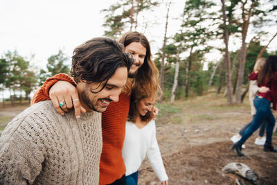 Cheerful man walking with friends in forest