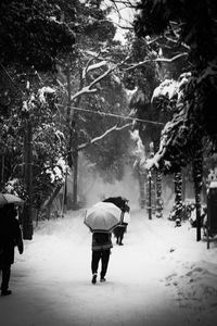 Rear view of man walking on snow covered road